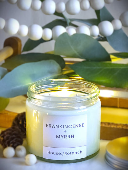 frankincense and myrrh candle in clear jars with silver metal lids with festive decorations in the background.