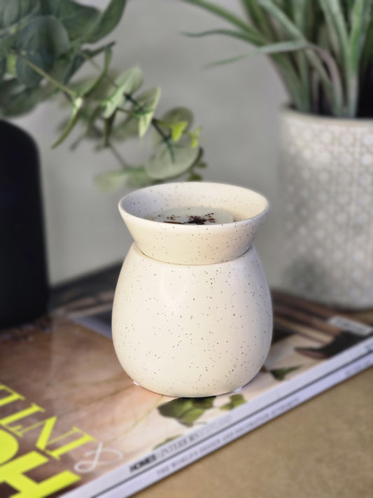 cream ceramic burner sitting on magazines with plants in the background